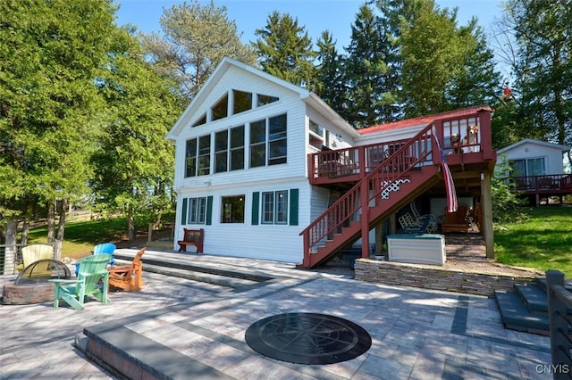 rear view of property featuring a fire pit, stairs, a wooden deck, and a patio area