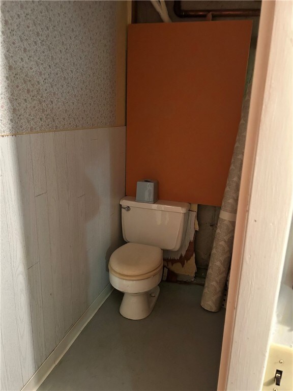 954 Graylea Cir, Elmira, NY 14905 - bathroom featuring a wainscoted wall, wood walls, toilet, finished concrete floors, and wallpapered walls