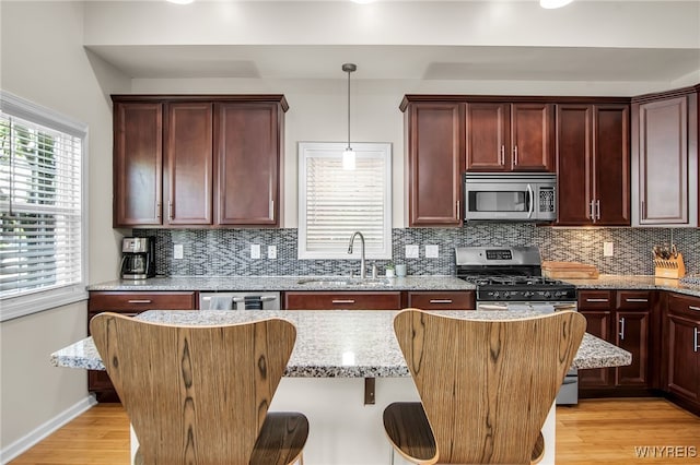 185 York St Unit 1, Buffalo, NY 14213 - kitchen with appliances with stainless steel finishes, a sink, a breakfast bar, backsplash, and hanging light fixtures