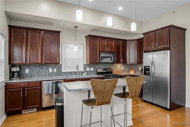 185 York St Unit 1, Buffalo, NY 14213 - kitchen featuring stainless steel appliances, a sink, light wood-type flooring, decorative backsplash, and light stone counters