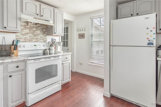 71 Champion St, Champion, NY 13619 - kitchen featuring white appliances, under cabinet range hood, decorative backsplash, dark wood finished floors, and baseboards