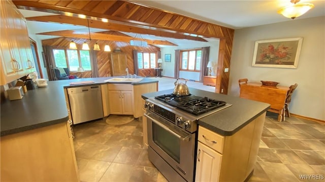 kitchen with stainless steel appliances, a sink, dark countertops, pendant lighting, and a peninsula