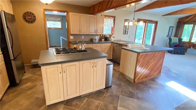 kitchen featuring stainless steel appliances, a sink, dark countertops, a peninsula, and plenty of natural light