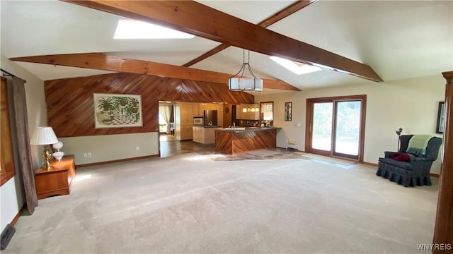 unfurnished living room featuring a skylight, light carpet, beamed ceiling, baseboards, and wood walls