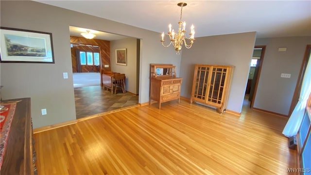 dining area with a chandelier, light wood-style floors, and baseboards