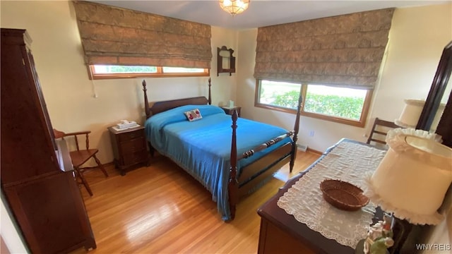 bedroom featuring multiple windows, light wood-style floors, and baseboards