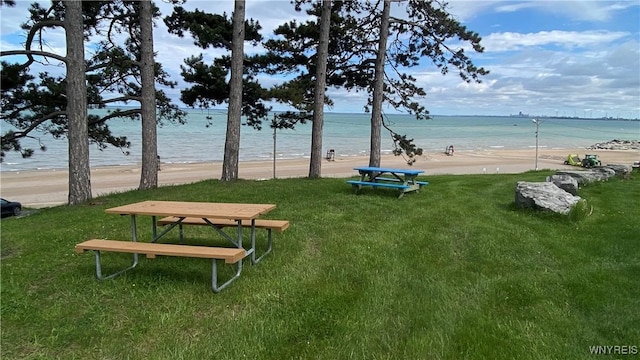view of home's community featuring a yard and view of water and beach