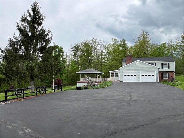 8584 Vieley Rd, Campbell, NY 14821 - view of front of property featuring asphalt driveway, a chimney, an attached garage, and view of scattered trees