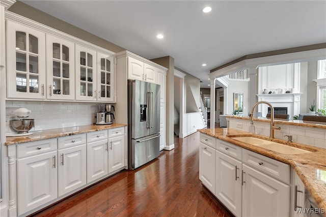 kitchen featuring high end fridge, a sink, glass insert cabinets, dark wood-style flooring, and white cabinetry