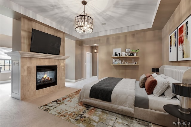 carpeted bedroom with a chandelier, a tiled fireplace, and baseboards