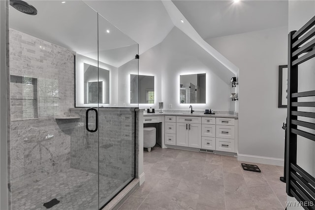bathroom with a shower stall, lofted ceiling, vanity, and baseboards