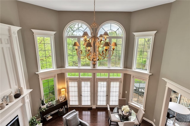 living area featuring a high end fireplace, a high ceiling, a chandelier, and dark wood finished floors