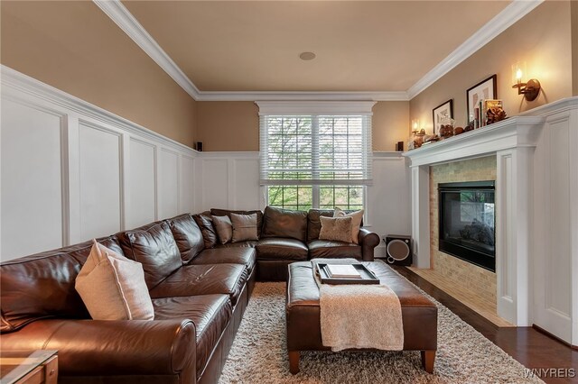 living room with a decorative wall, ornamental molding, wood finished floors, a fireplace, and a wainscoted wall