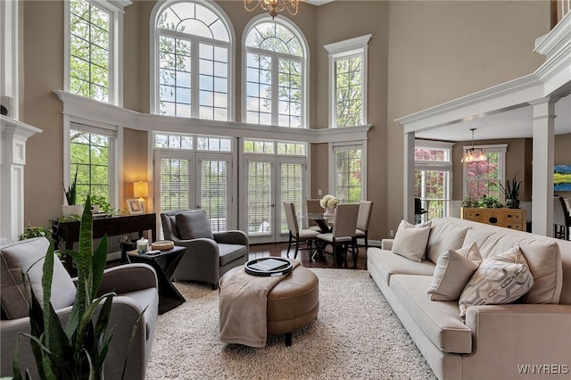 living room featuring a high ceiling, a chandelier, and ornate columns