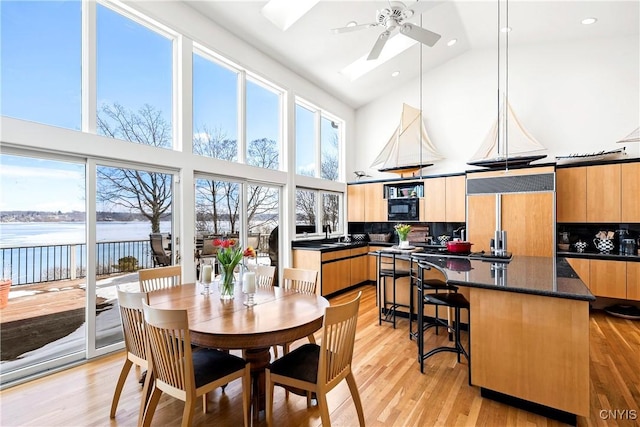 5598 Buck Point Rd, Fleming, NY 13021 - dining space with high vaulted ceiling, a ceiling fan, a water view, light wood-style floors, and recessed lighting