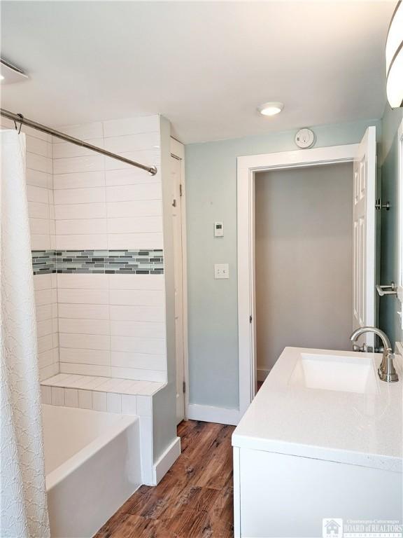 55 Washington Ave, Pomfret, NY 14063 - bathroom featuring wood finished floors, shower / bathtub combination with curtain, vanity, and baseboards
