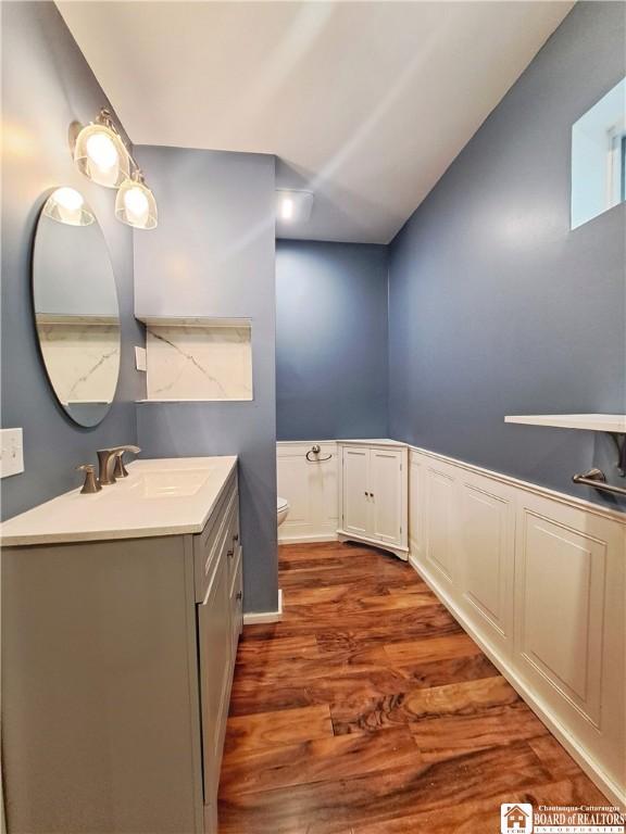 55 Washington Ave, Pomfret, NY 14063 - bathroom featuring toilet, wood finished floors, vanity, and a wainscoted wall