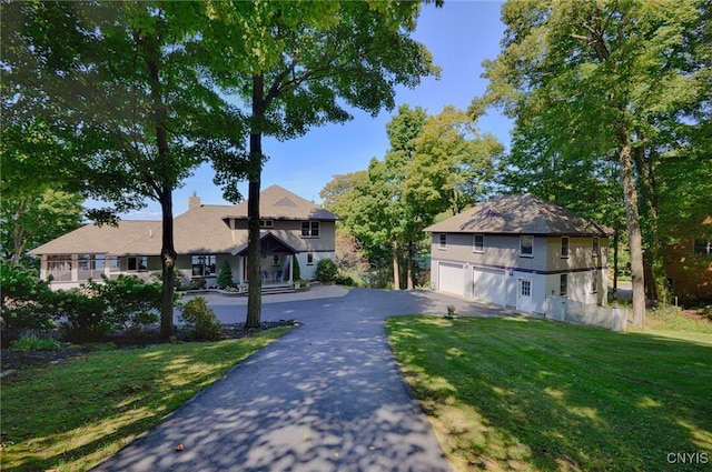view of front facade with asphalt driveway, a front yard, and an attached garage