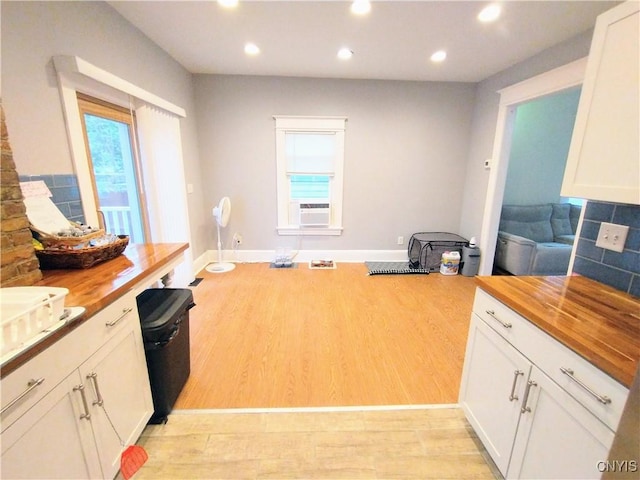 kitchen with wood counters, light wood-style flooring, recessed lighting, white cabinets, and baseboards