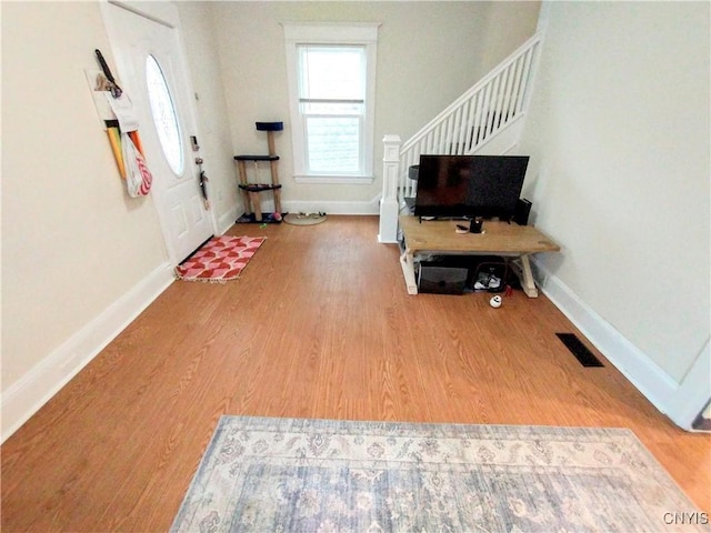 foyer entrance with wood finished floors, stairway, and baseboards