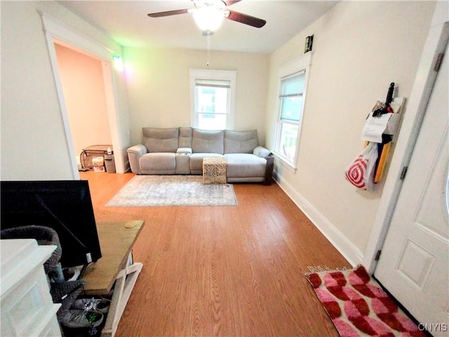 living area with wood finished floors, a ceiling fan, and baseboards