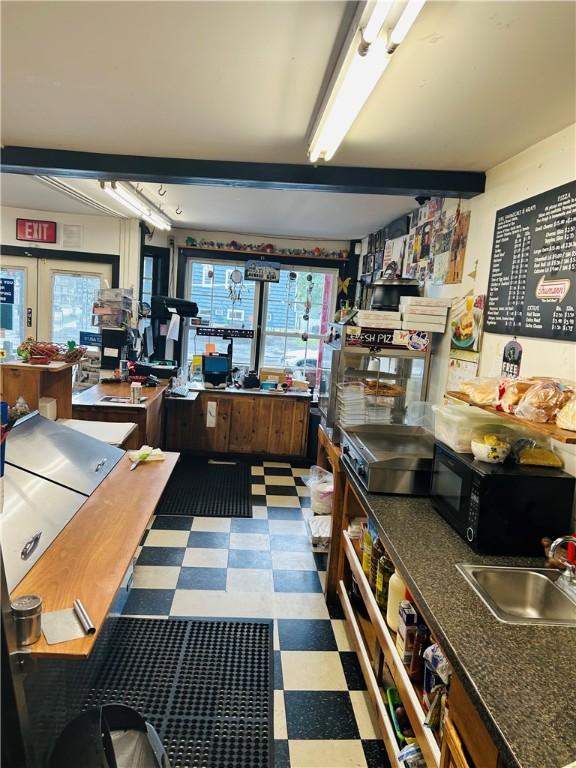 69 S Main St, Milford, NY 13807 - kitchen featuring tile patterned floors, black microwave, healthy amount of natural light, beam ceiling, and a sink