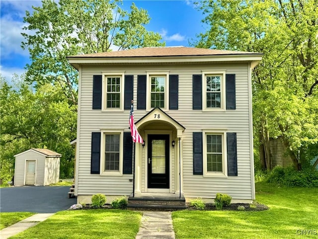 colonial-style house featuring an outbuilding and a front yard