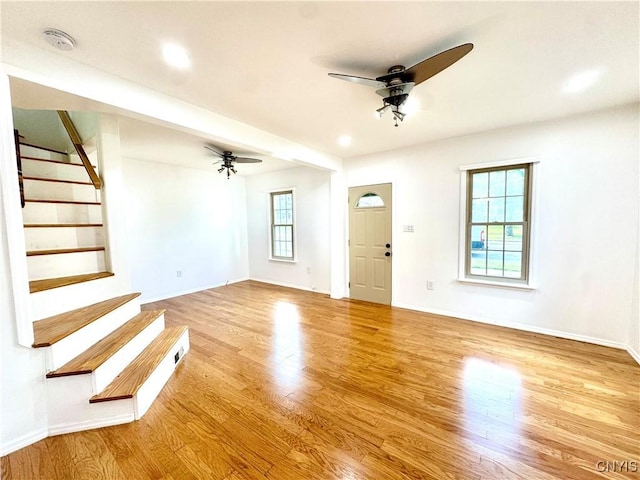 unfurnished living room with ceiling fan, wood finished floors, stairway, baseboards, and recessed lighting