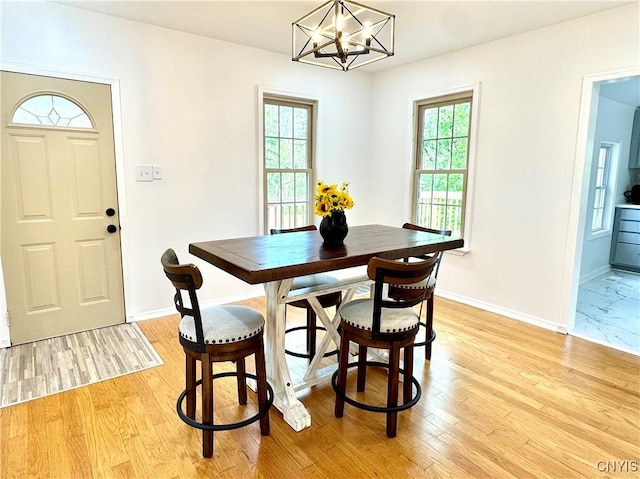 dining room with a chandelier, baseboards, and light wood finished floors