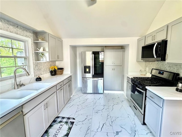 kitchen featuring appliances with stainless steel finishes, vaulted ceiling, a sink, light marble finish floors, and open shelves