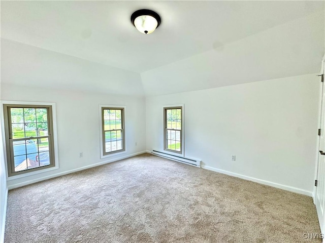 spare room featuring a baseboard heating unit, carpet flooring, baseboards, and vaulted ceiling
