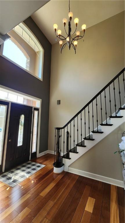 31 Putney Pl, Greece, NY 14468 - foyer entrance with baseboards, hardwood / wood-style floors, a chandelier, stairs, and a towering ceiling