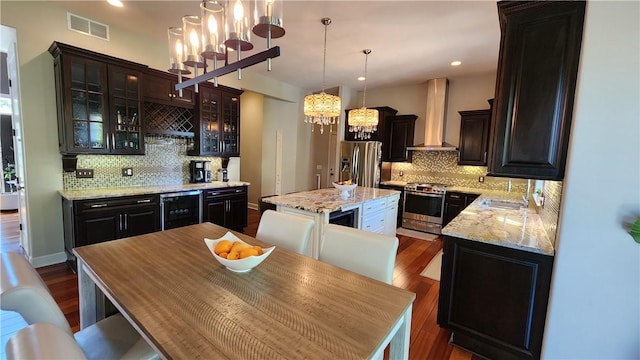 31 Putney Pl, Greece, NY 14468 - kitchen featuring appliances with stainless steel finishes, wall chimney range hood, a chandelier, tasteful backsplash, and wine cooler