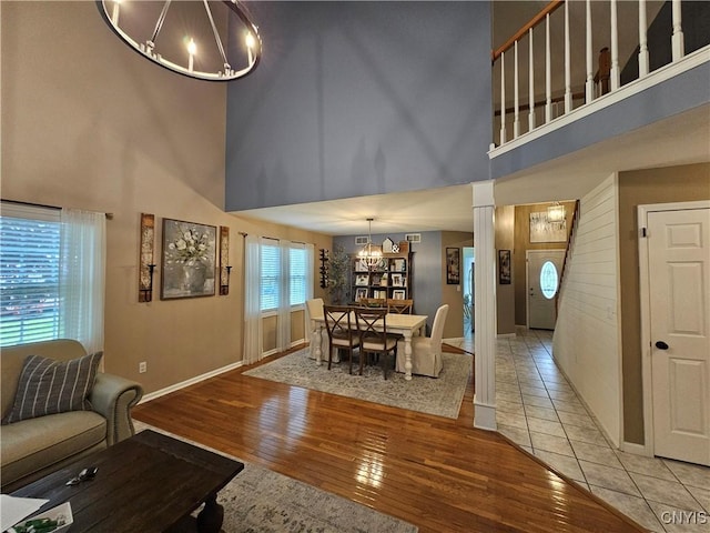 108 Sunflower Cir, Frankfort, NY 13340 - living area featuring a towering ceiling, a chandelier, decorative columns, light wood-style floors, and baseboards