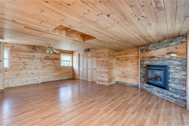 20304 Burton Rd, Hounsfield, NY 13685 - unfurnished living room featuring wood ceiling, wood finished floors, wood walls, a stone fireplace, and a ceiling fan