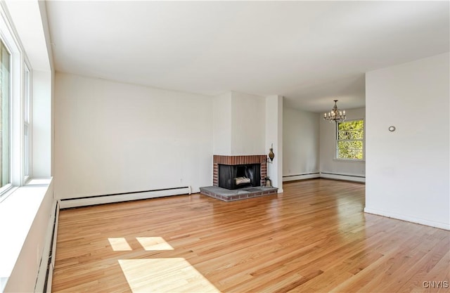 18 Court Knolle, New Hartford, NY 13413 - unfurnished living room with baseboard heating, a chandelier, light wood-style floors, and a brick fireplace
