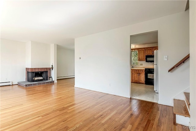 18 Court Knolle, New Hartford, NY 13413 - unfurnished living room featuring baseboard heating, stairway, light wood-type flooring, and a fireplace