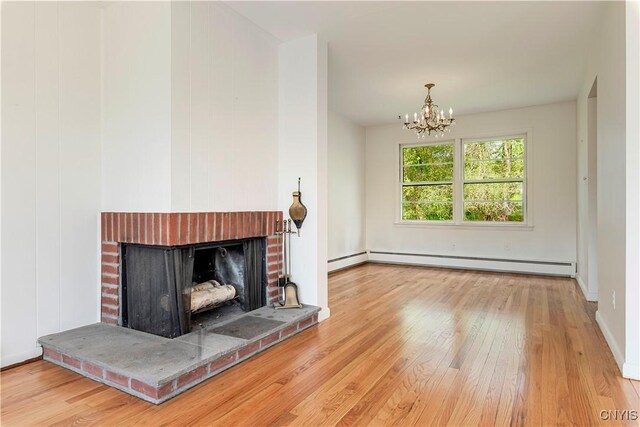 18 Court Knolle, New Hartford, NY 13413 - unfurnished living room featuring a baseboard heating unit, wood finished floors, a chandelier, and a brick fireplace