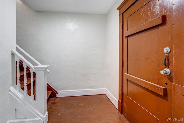 foyer with wood finished floors, baseboards, and stairway