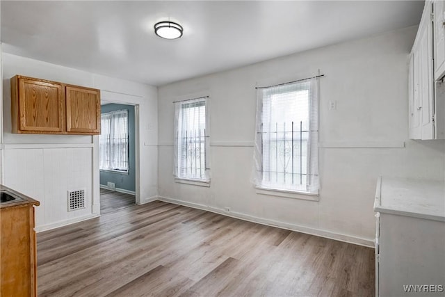 unfurnished dining area featuring light wood-style floors and baseboards