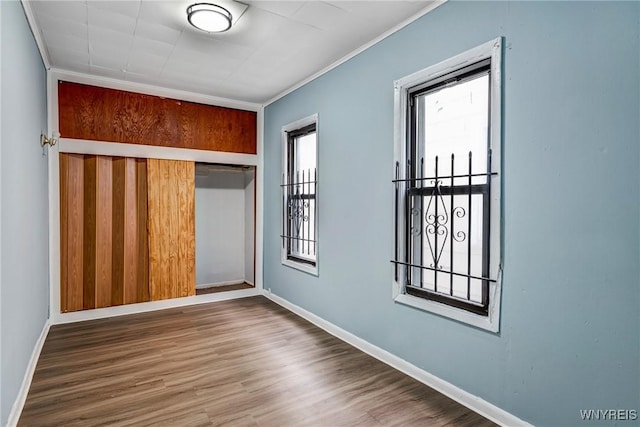 unfurnished room featuring wood finished floors, baseboards, and ornamental molding