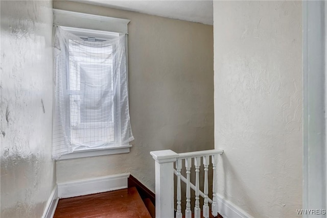 staircase featuring plenty of natural light, wood finished floors, and baseboards