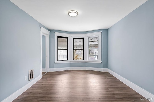empty room featuring baseboards and dark wood-type flooring