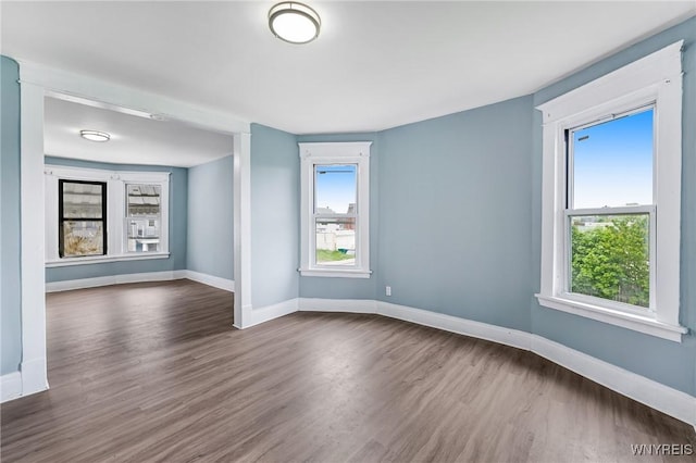 spare room featuring dark wood-type flooring and baseboards