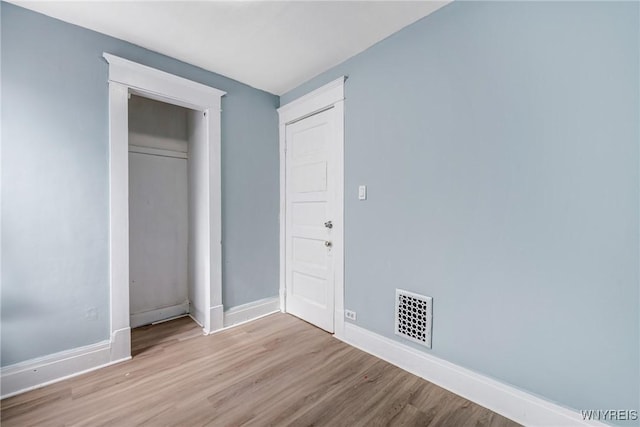unfurnished bedroom with wood finished floors, baseboards, and a closet