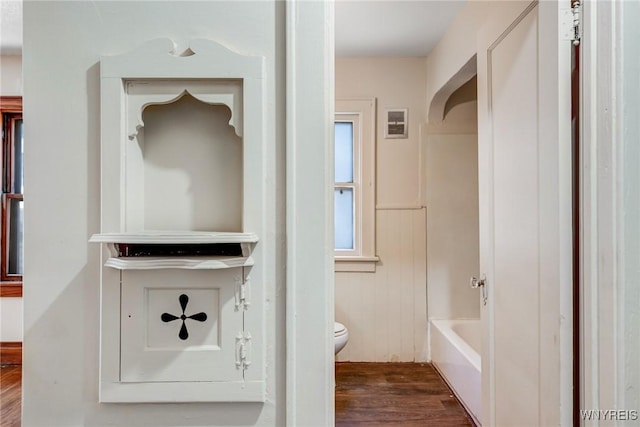 27 E End Ave, Cheektowaga, NY 14225 - full bathroom featuring wood finished floors, toilet, a tub to relax in, and wainscoting