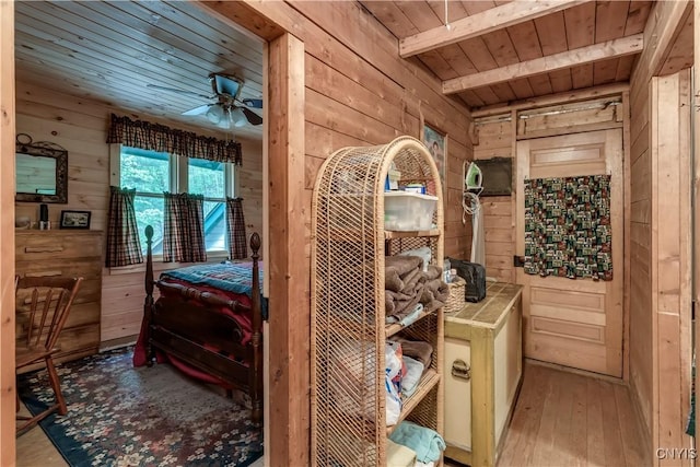bedroom featuring wooden walls, wooden ceiling with exposed beams, and hardwood / wood-style flooring