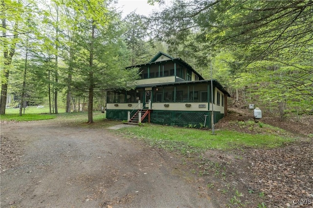 view of front of property featuring a sunroom and a wooded view
