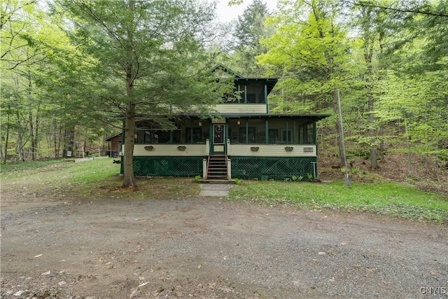 view of front of home featuring a sunroom and a view of trees