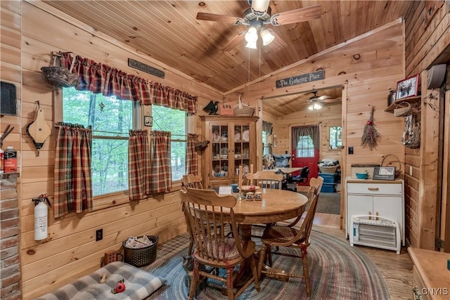 dining space with wooden ceiling, ceiling fan, wooden walls, vaulted ceiling, and wood finished floors